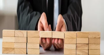 Mergers and acquisitions streamlining being shown using wooden blocks